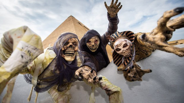 Drei als Mumien verkleidete Menschen vor einer Pyramide